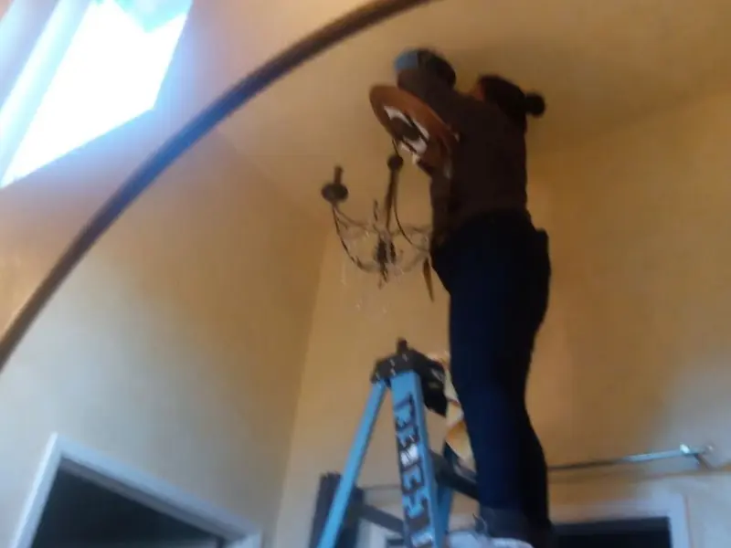 Electrician installing a chandelier in a Bellmead residence